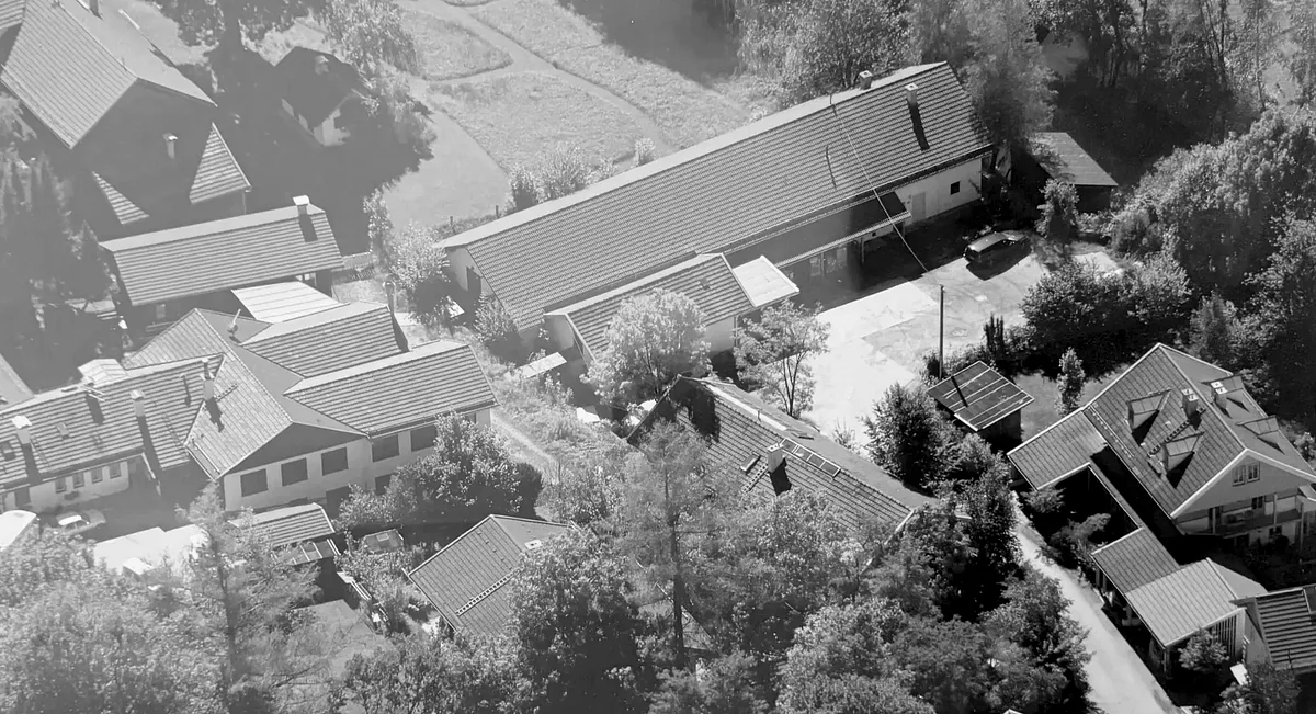 Historische Schwarz-Weiß-Luftaufnahme des ersten eigenen HiWo-med-Standorts „An der Ach“ in Uffing am Staffelsee.